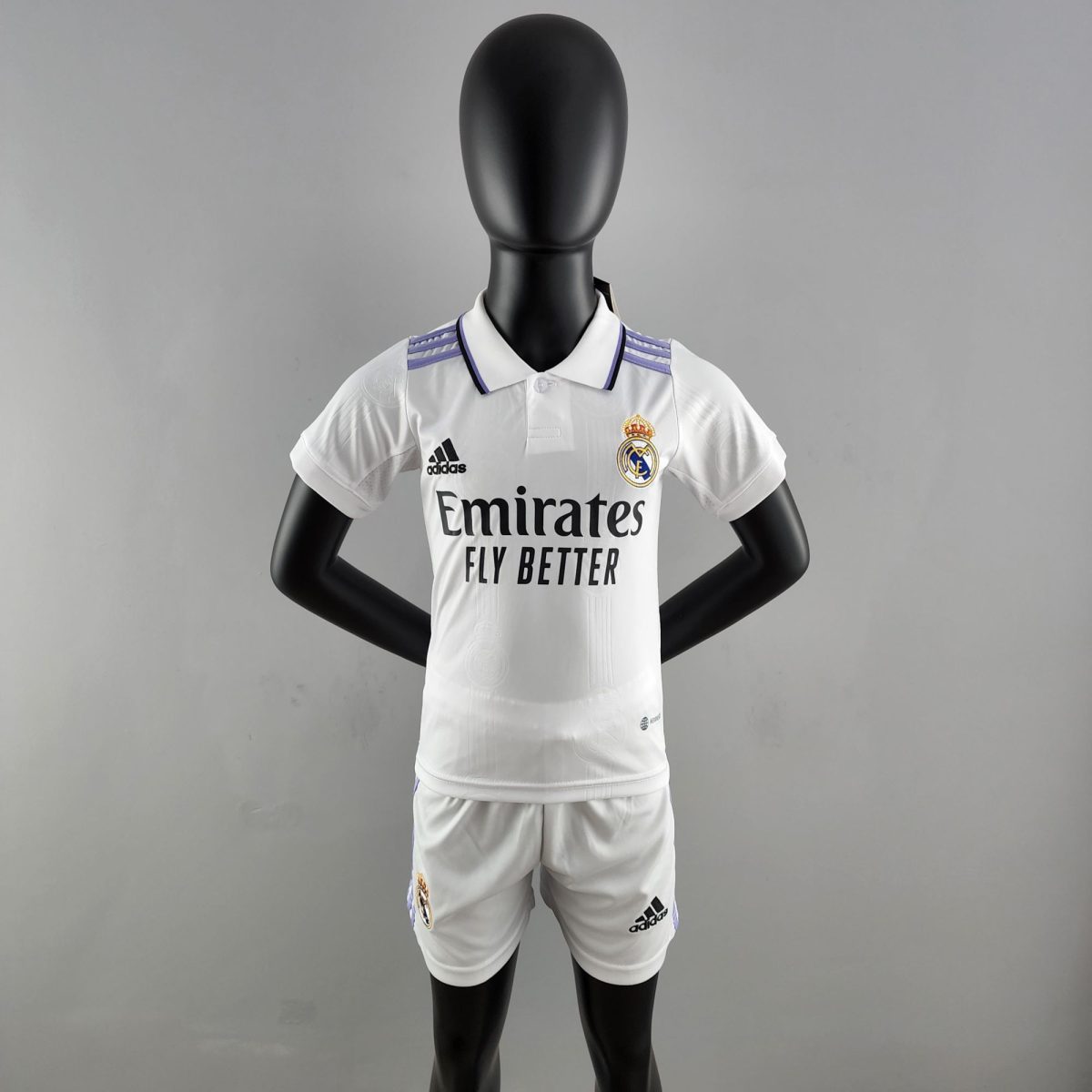 Mannequin wearing a Real Madrid white soccer jersey with purple shoulder stripes, standing against a gray background.