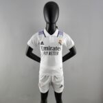 Mannequin wearing a Real Madrid white soccer jersey with purple shoulder stripes, standing against a gray background.