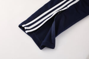 Navy blue athletic pants with white side stripes and a zippered ankle cuff (close-up)