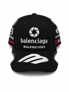 Black Balenciaga cap with white embroidered logos on the front and sides and a curved brim.