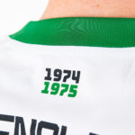 Back of a white jersey with a green collar, showing the years 1974 (black) and 1975 (green).