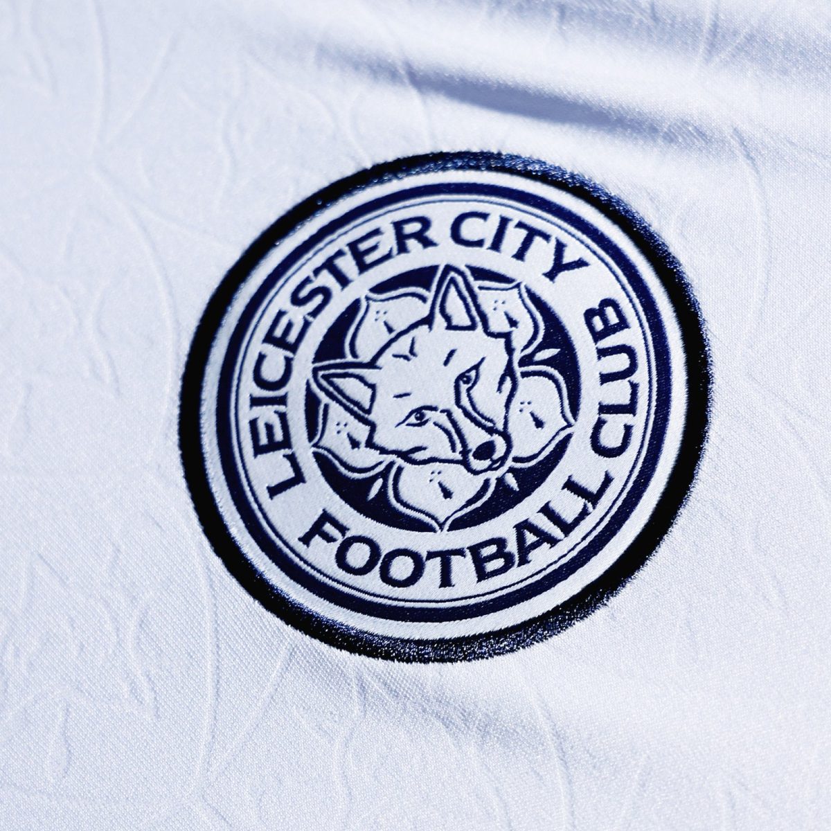 Close-up of a Leicester City Football Club crest embroidered on white fabric.