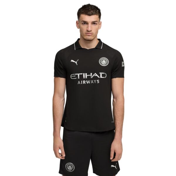 Young man in a black Manchester City football jersey with sponsor Etihad Airways and club crest, facing camera.