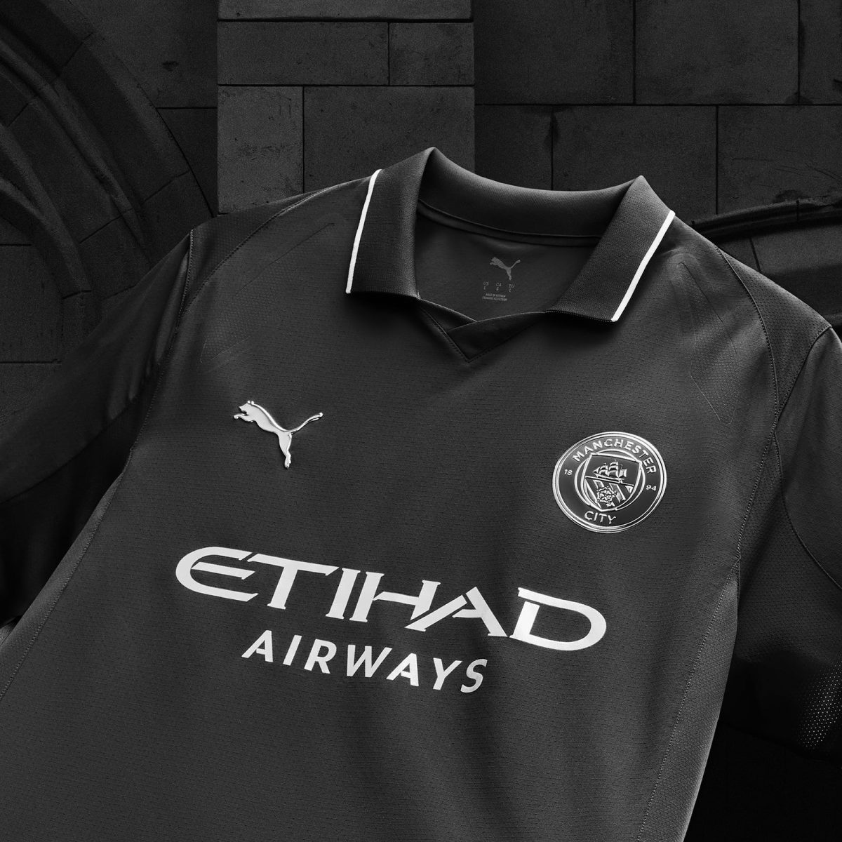 Black Manchester City football jersey featuring Etihad Airways sponsor, Puma logo, and club crest seen on chest plate edge.