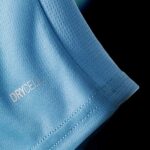 Close-up of blue textured fabric with visible perforations and stitching, showing part of the word 'DRYCELL' stitched on.