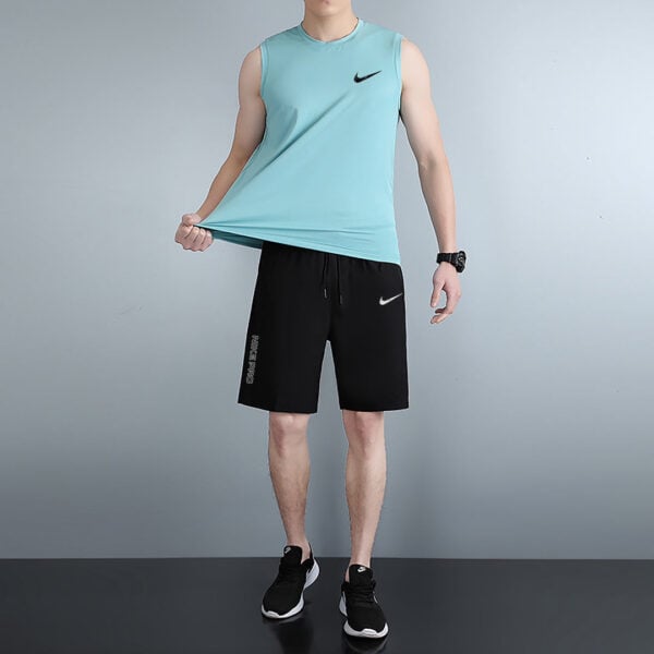 Man modeling a turquoise sleeveless athletic top with black Nike shorts and black sneakers.