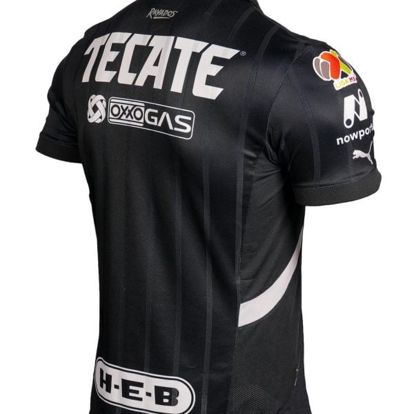 Back view of a black racing jersey with large Tecate logo, vertical stripes, and sponsor patches (Oxogas, H-E-B) on the lower back and sleeve area