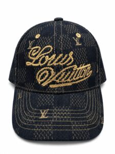 Dark denim baseball cap with gold embroidery reading Louis Vuitton on the front panel and brim stitching in gold thread