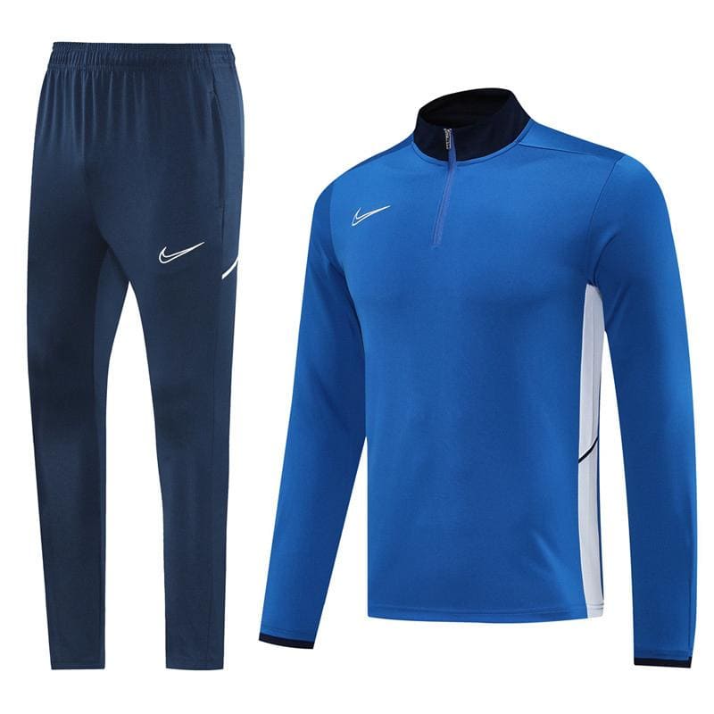 712d287e-636e-46ad-be72-975c264b1549 | UAE SPORT STORE Nike blue athletic tracksuit: zip-up top with white Nike swoosh and matching navy jogger pants on white background, side white panels on the shirt.