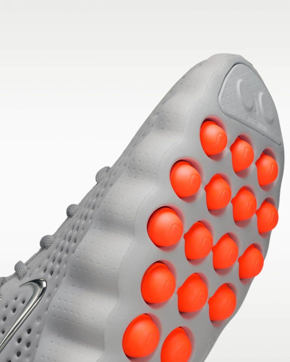 Close-up of a gray athletic shoe showcasing orange traction studs on the sole.