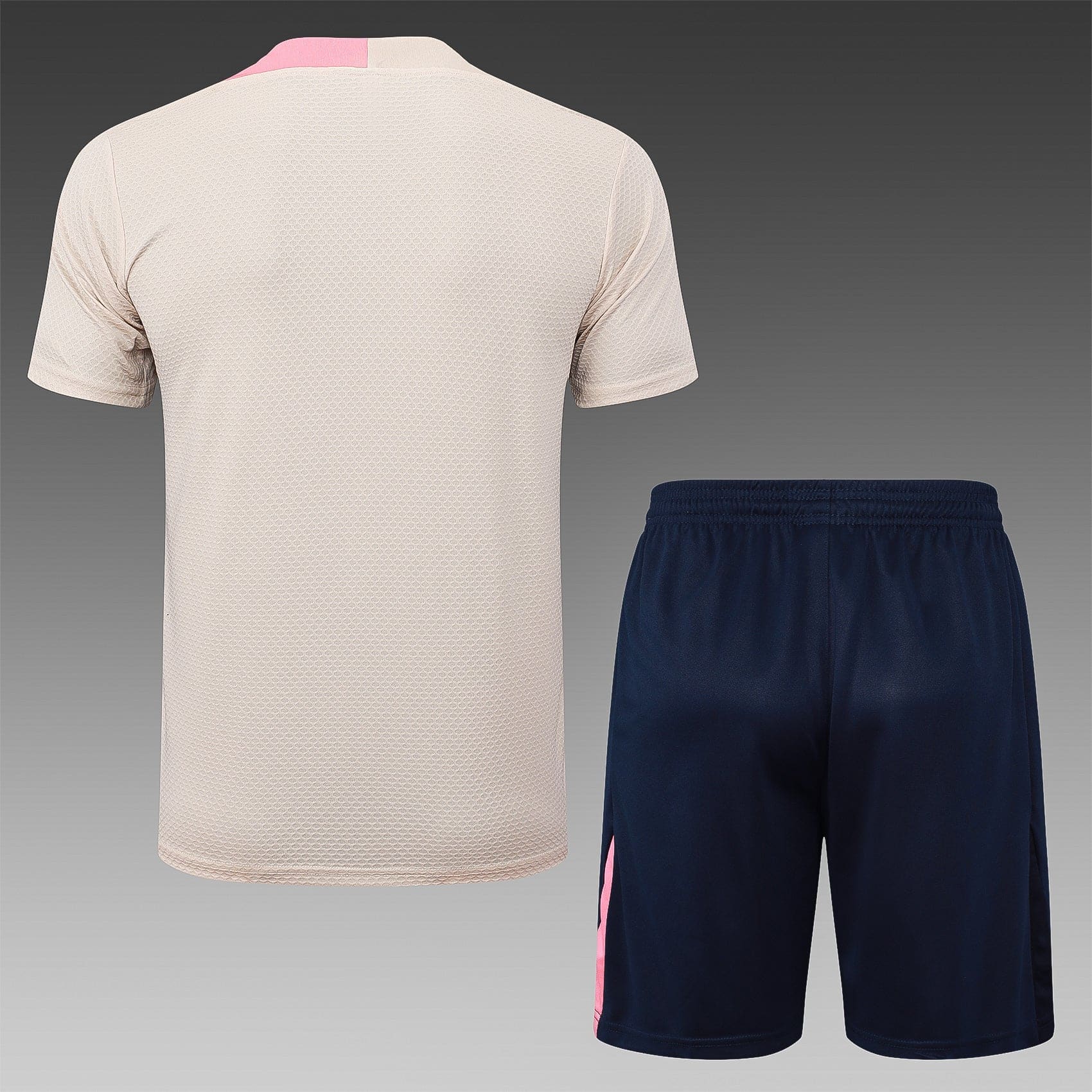 716140ce | UAE SPORT STORE Back view of a beige textured athletic shirt paired with navy shorts featuring a pink stripe along the side.