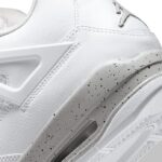 Close-up of a white athletic sneaker showing stitched panels, a cutout side support, and a speckled gray sole with an air unit.