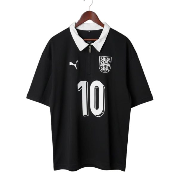 Black soccer jersey with a white collar, crest on the chest, Puma logo, and the number 10 on the front, hanging on a wooden hanger
