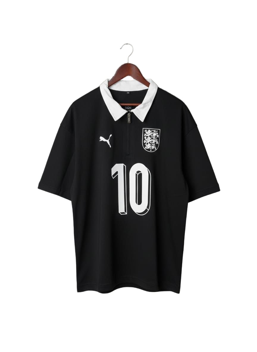 Black soccer jersey with a white collar, crest on the chest, Puma logo, and the number 10 on the front, hanging on a wooden hanger