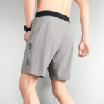 Back view of a man wearing gray Nike athletic shorts with a black waistband and side logo.