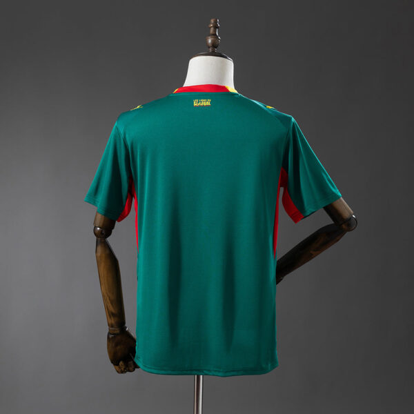 Back view of a teal-green soccer jersey with red side panels on a mannequin, small yellow label at the collar.