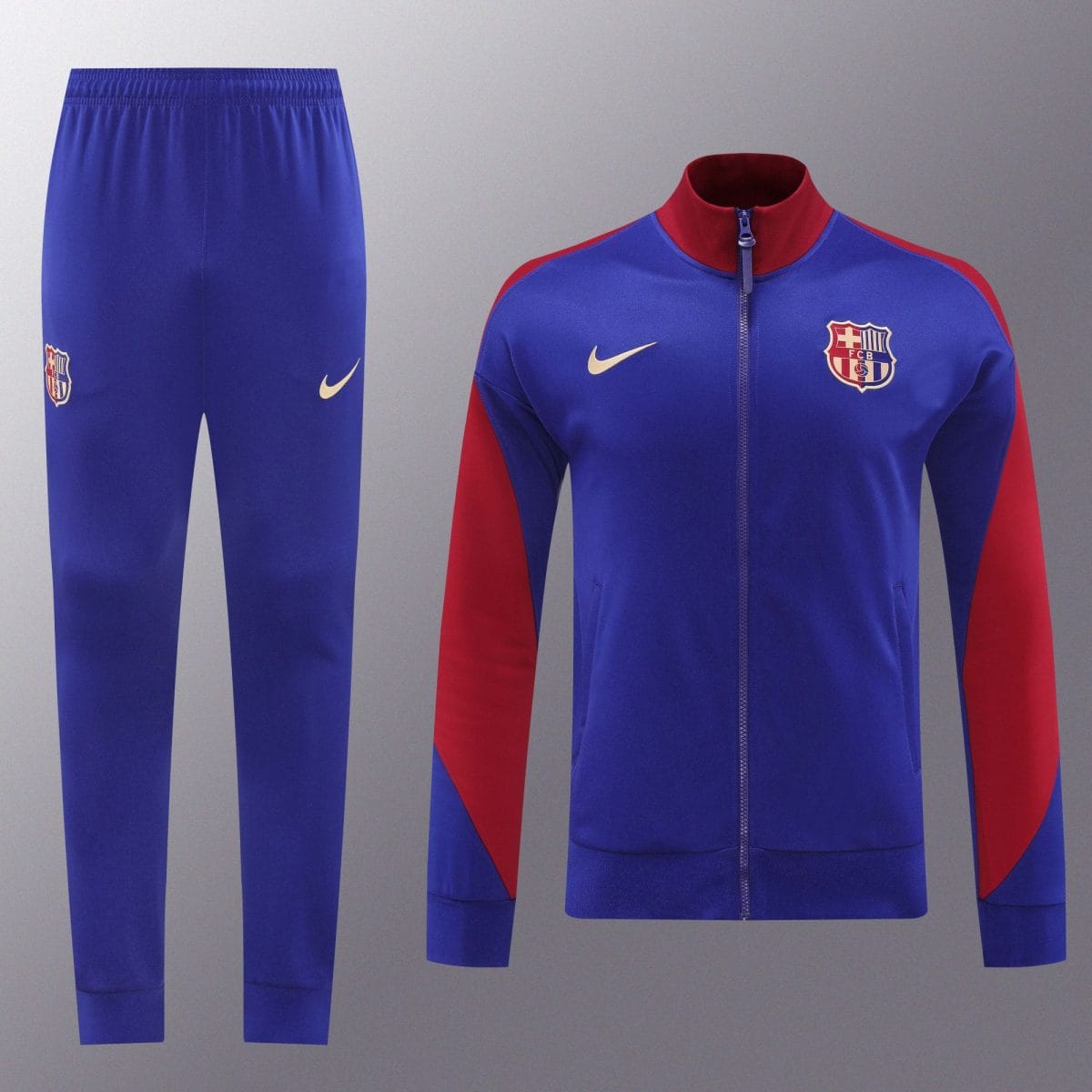 Blue FC Barcelona tracksuit jacket with red accents and the club crest, paired with matching blue pants with a Nike swoosh. It shows a sporty training outfit.