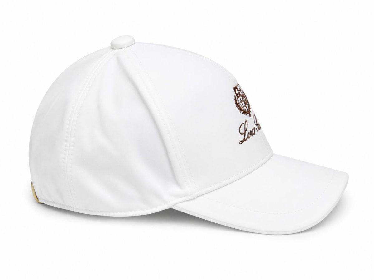 White baseball cap with a curved brim and brown embroidered crest and script on the front