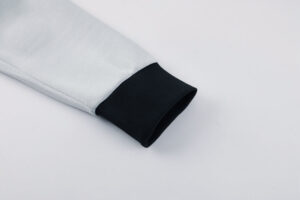 Close-up of a light gray sleeve ending with a black ribbed cuff.