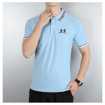 Light blue polo shirt on a model, polo collar with branding and Under Armour logo on the chest.