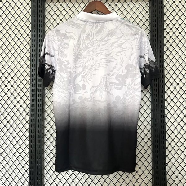 White polo shirt with subtle dragon pattern fading to black at the hem, hanging on a wooden hanger against a metal grid backdrop.