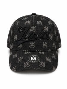 74f71b4a-7941-4ea3-b0be-c697f33f7a52 | UAE SPORT STORE Black denim baseball cap with a repeated light logo pattern and a large embroidered cursive 'Amiri' on the front; round metal sticker on the brim.