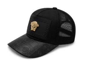 753bacc5-3bcc-4543-808a-1f07564f6537 | UAE SPORT STORE Black trucker cap with a decorative black panel and gold Medusa-style emblem on the front, and a patterned brim with a geometric design.