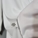 75405076_b2b32875-5906-45fa-862b-de6d67c86d2d | UAE SPORT STORE Close-up of white fabric with a clothing tag showing numbers 134748 ASR001/09 01/03