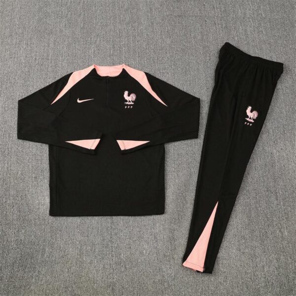 Black long-sleeve athletic top with pink panels and a pink rooster crest (FFF) beside a Nike swoosh, matching pink-accent pants beside it, on a gray background. More concise: France football training suit with pink accents and FFF crest.
