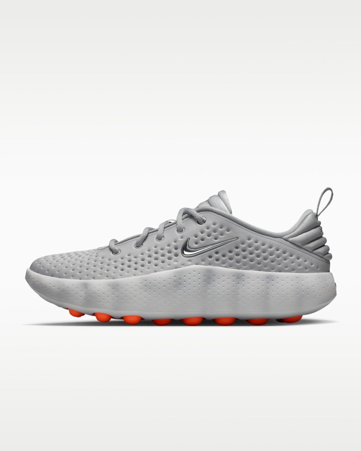 Grey athletic sneaker with a perforated upper, white midsole, and orange cleat studs visible on the outsole (Nike swoosh logo shown).