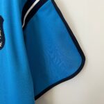 Close-up of bright blue mesh fabric with dark navy seam along the edge, suggesting a backpack or sportswear item.