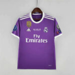 Purple Real Madrid football jersey on hanger with Fly Emirates sponsor and white Adidas stripes on shoulders.