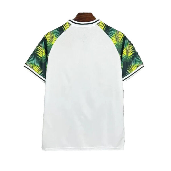 Back view of a white polo shirt with tropical palm leaf-patterned raglan sleeves and black-and-white collar trim on a hanger