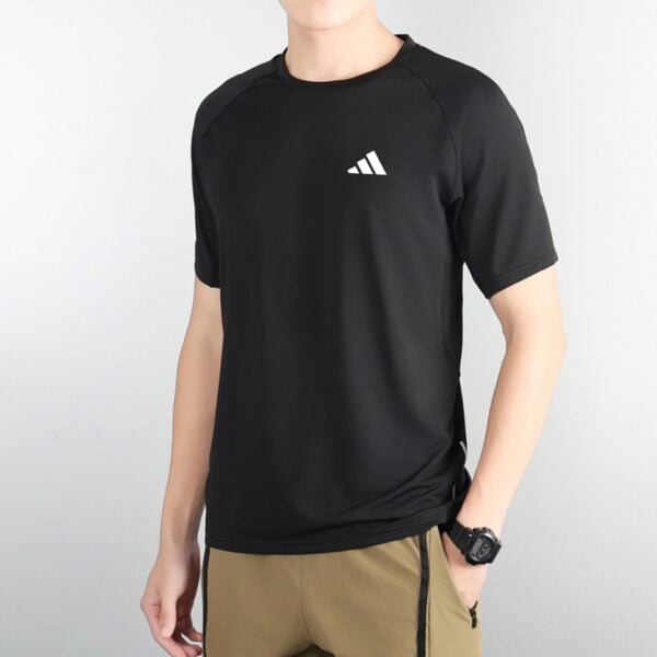 Person wearing a black athletic shirt with a small white three-stripe logo on the chest, paired with tan cargo shorts.