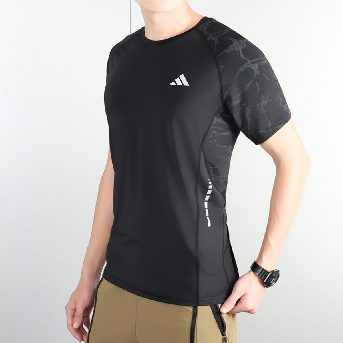 Man wearing a black athletic shirt with a small white Adidas logo on the chest and gray marbled sleeves