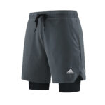 76ee7f66_b9eebb5e-4b63-45b6-927d-0a3754f2d695 | UAE SPORT STORE Athletic gray Adidas shorts with black drawstring, layered over black compression shorts, front view.