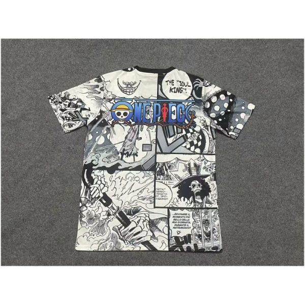 White manga-collage T-shirt featuring One Piece branding and comic panels, laid flat on a gray carpet.