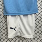 Close-up of blue athletic fabric laid over a white garment with a navy Puma logo, on a black grid background.