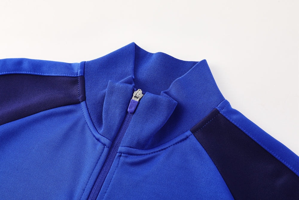 773a3e22 | UAE SPORT STORE Close-up of a blue zip-up jacket showing the collar and zipper detail.