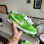 Bright lime green Nike sneaker with white swoosh being held by a hand indoors