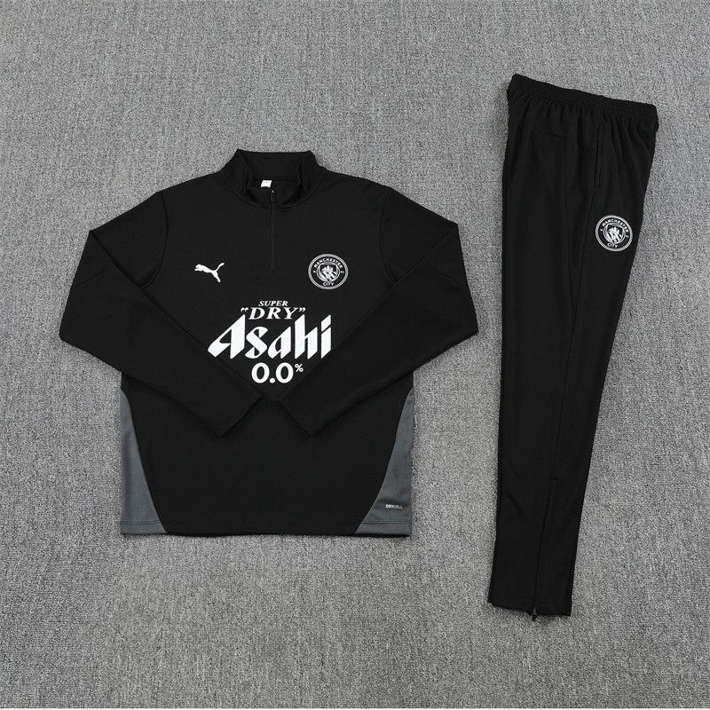 7774ee46-73c1-44cb-b042-269e53eac44f | UAE SPORT STORE Black athletic tracksuit laid flat: pullover top with logo and sponsor text, and matching pants with crest patch, on a gray carpet.