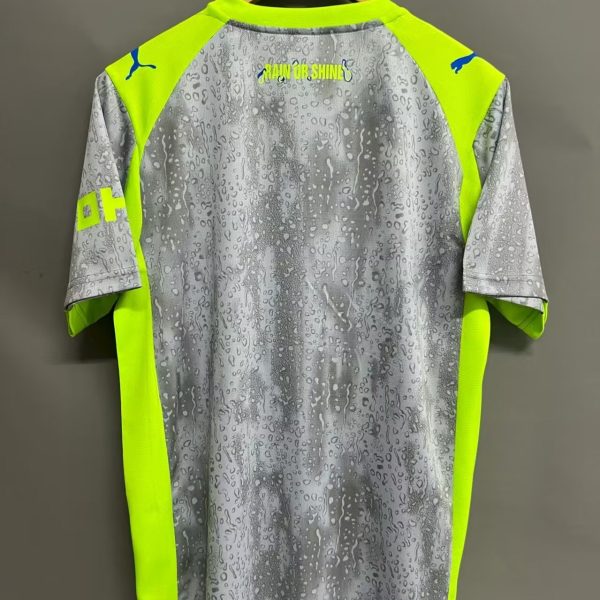 Back of a gray rain‑pattern jersey with neon yellow panels, hanging on a wooden hanger; 'RAIN OR SHINE' text on upper back.