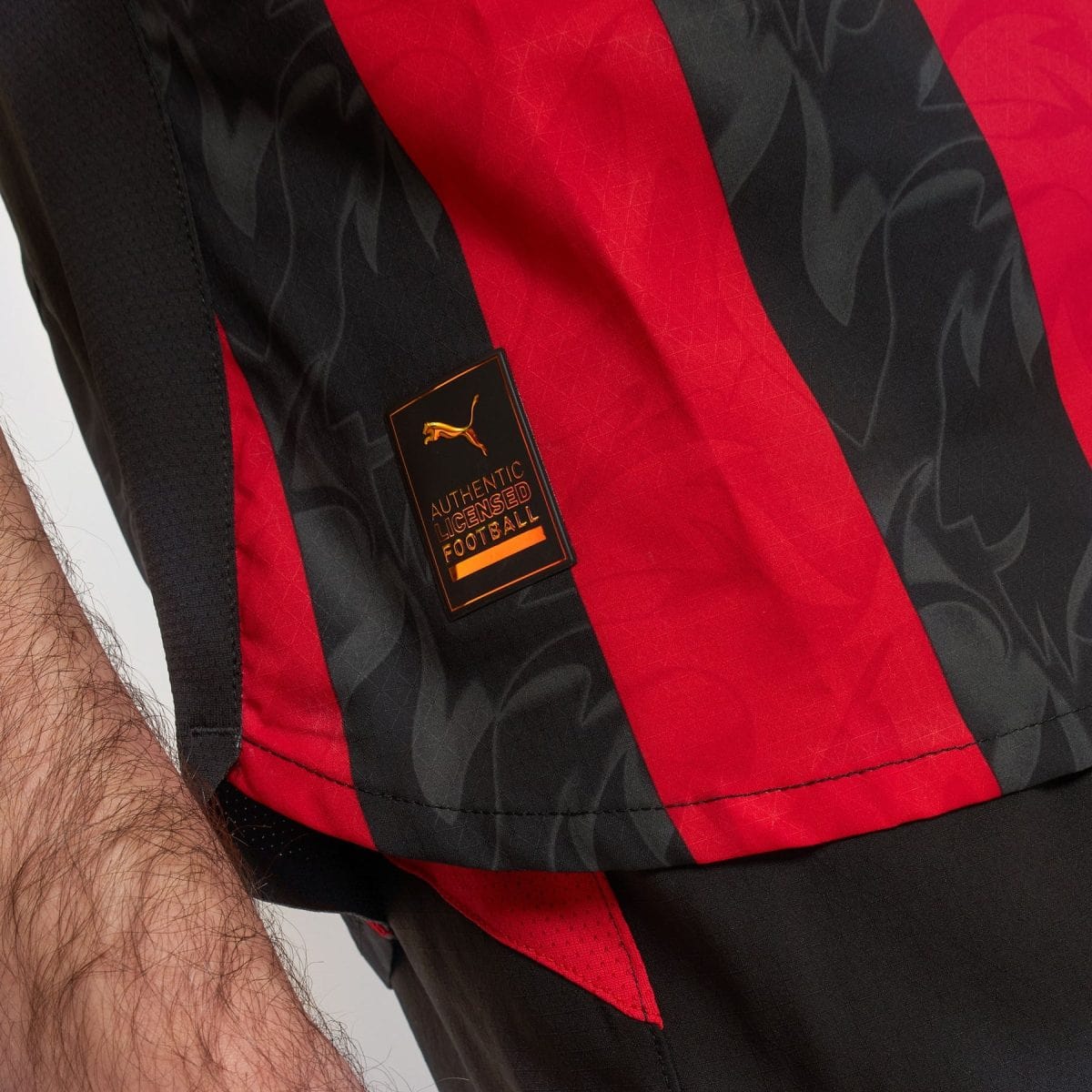 Close-up of a red and black striped football jersey fabric with a gold and black Authentic Licensed Football tag