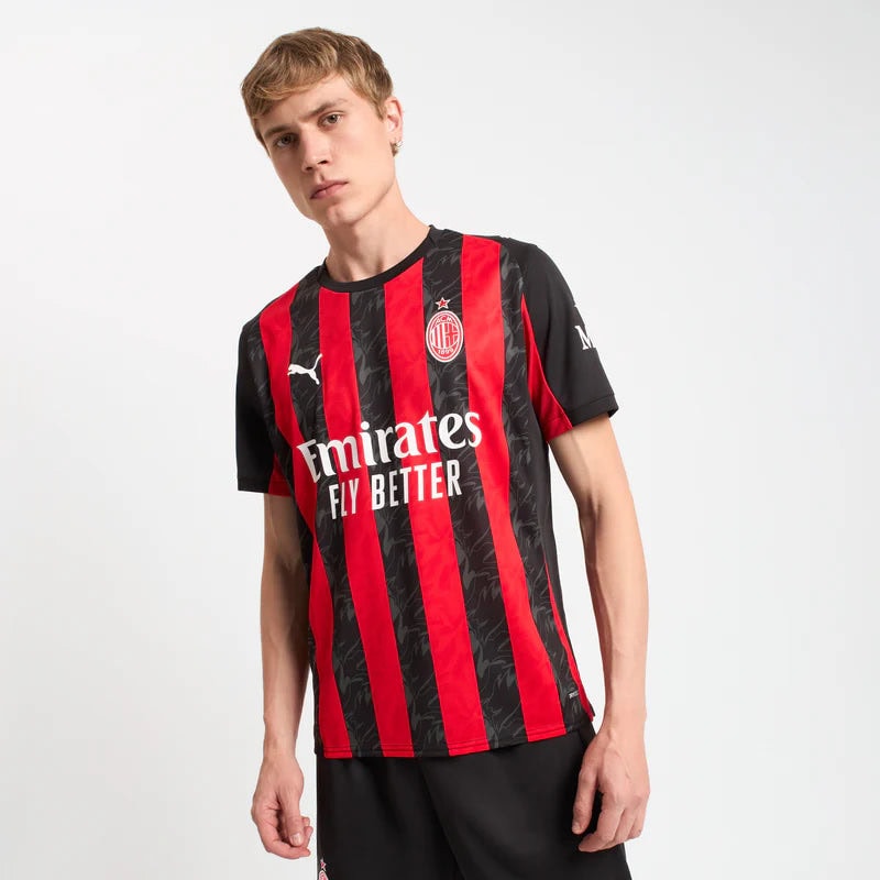 779962-A81_03_800x_c4748e9f-f7a3-4643-83eb-09a28b553626 | UAE SPORT STORE Man wearing red-and-black striped AC Milan jersey with Emirates Fly Better sponsor, standing with a slight lean against a white background.
