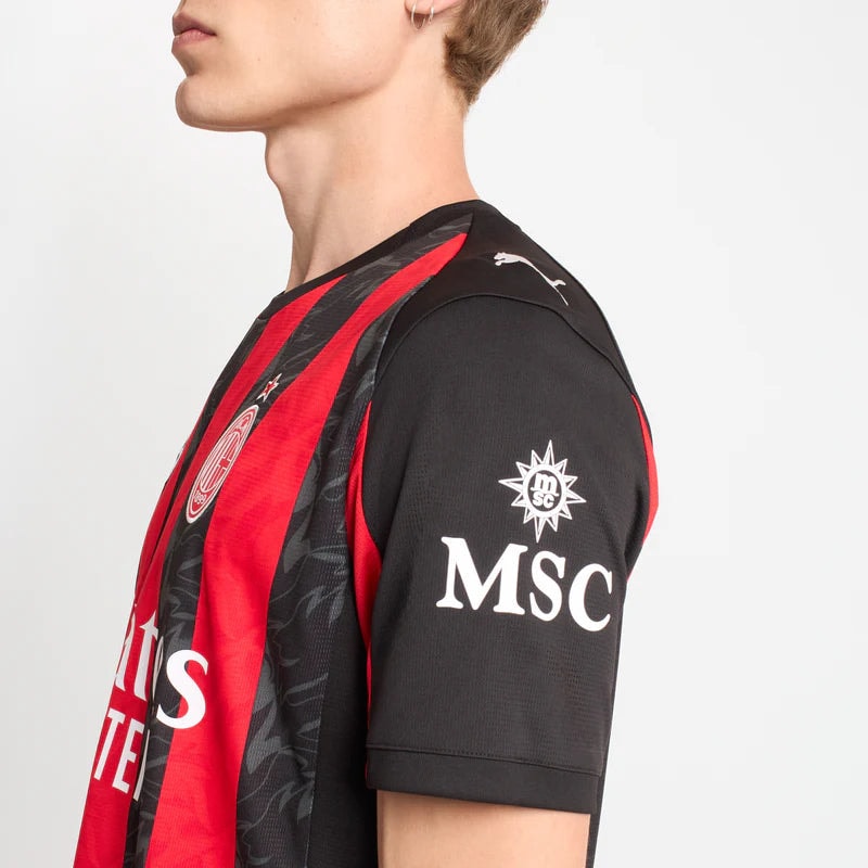 779962-A81_07_800x_9ffa669e-300b-4254-8777-bf981461ed1e | UAE SPORT STORE Side view of a person wearing a red-and-black striped soccer jersey with MSC on the sleeve and a crest on the chest.