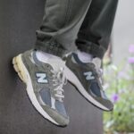 Pair of gray and blue New Balance sneakers resting on a ledge, showing the side N logo and chunky soles.