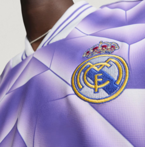 Close-up of a purple Real Madrid jersey showing the embroidered club crest with crown.