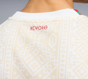 Back view of a person wearing a cream geometric knit sweater with a white collar and a red-green plaid shoulder detail.