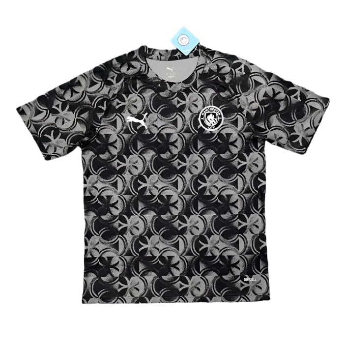 78f85b5774eefb57 Black and gray geometric-patterned soccer jersey with a Puma logo on the right chest and a circular club crest on the left, tag attached.