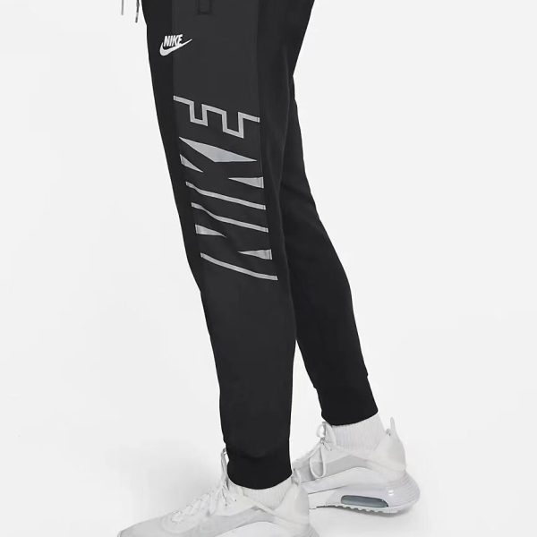 Person wearing black Nike joggers with gray geometric print along the leg, paired with white athletic sneakers.